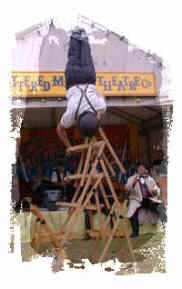 A Weatherman balanced precariously upon a tower of folding chairs.